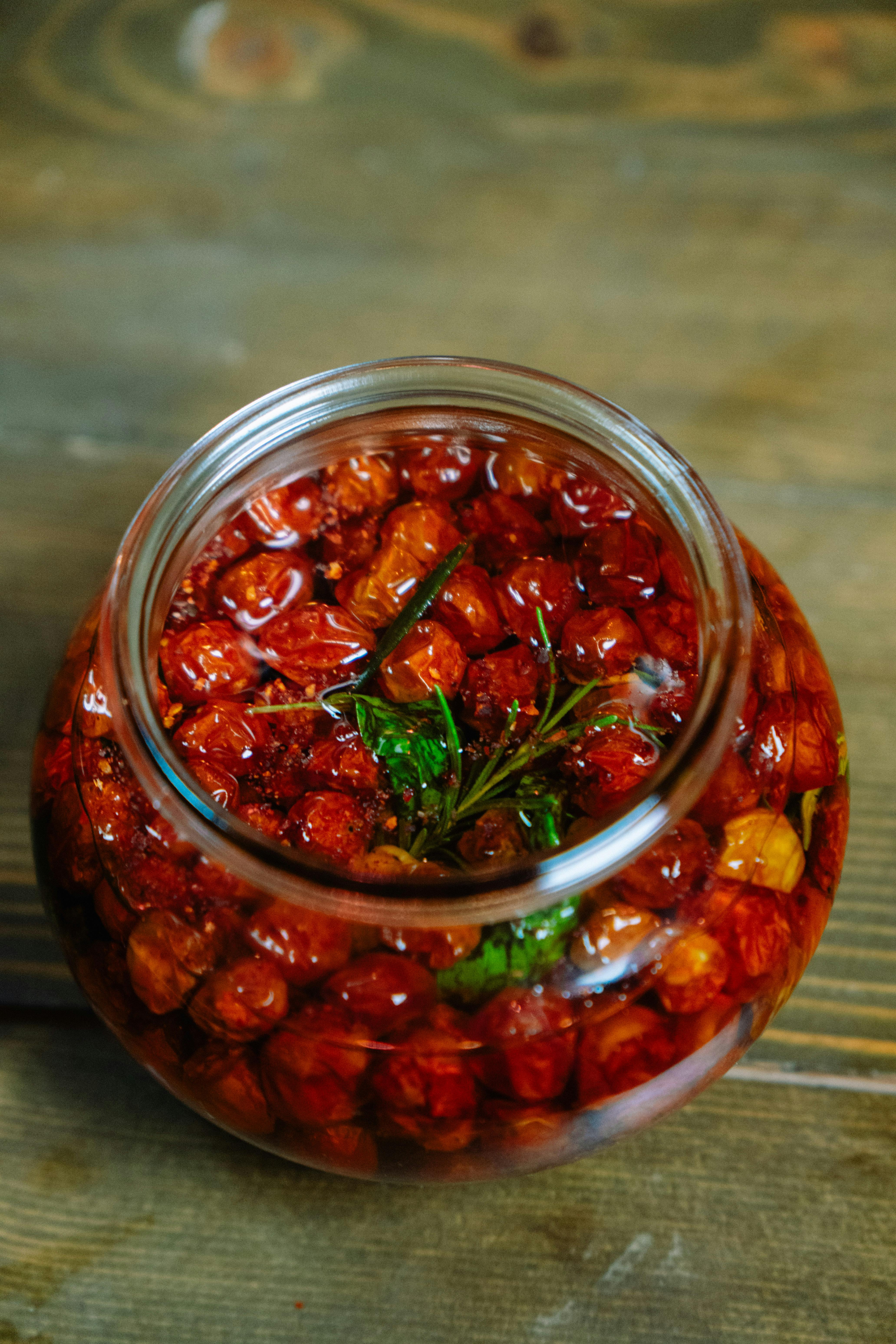 Jar of homemade sunblush tomatoes in olive oil with herbs, ready to use in salads, pasta and antipasti.